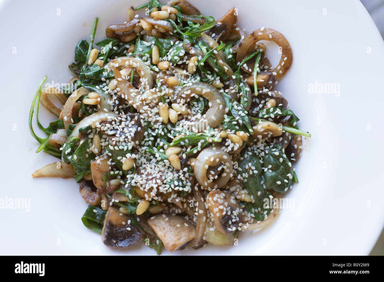 Vegan meal featuring Japanese miso paste, mushrooms, greens, onions and pine nuts.  Topped with sesame seeds. Stock Photo