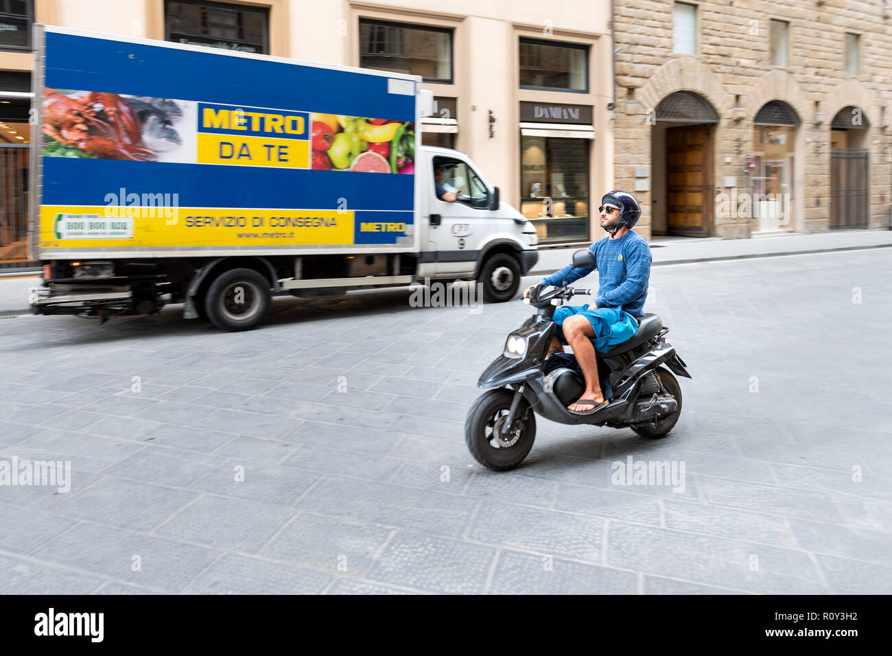 Florence, Italy - August 31, 2018: Panning shot of young Italian man riding, driving, moving on vespa scooter, motorcycle on street of Firenze, Italia Stock Photo