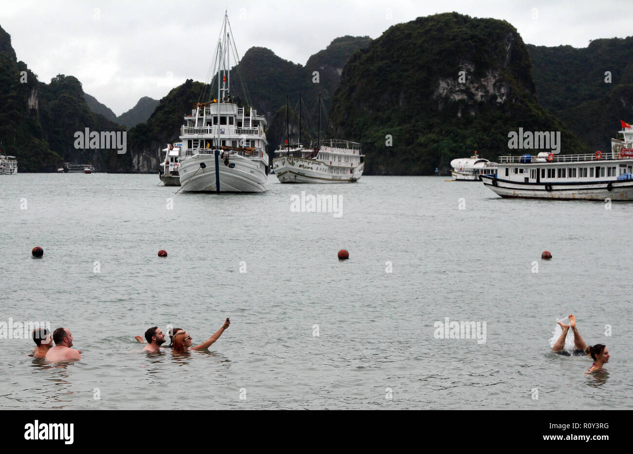 Group of tourists make selfies and handstands in the water, Ha Long Bay, Vietnam Stock Photo