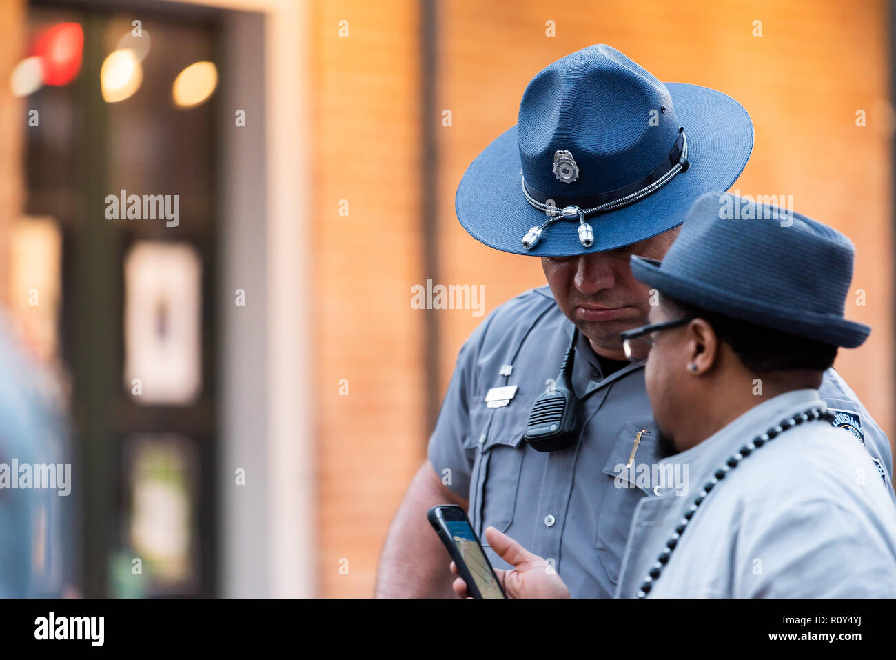 New Orleans, USA - April 22, 2018: Closeup of police officer man in hat talking to male lost tourist in old town Louisiana famous city in evening Stock Photo