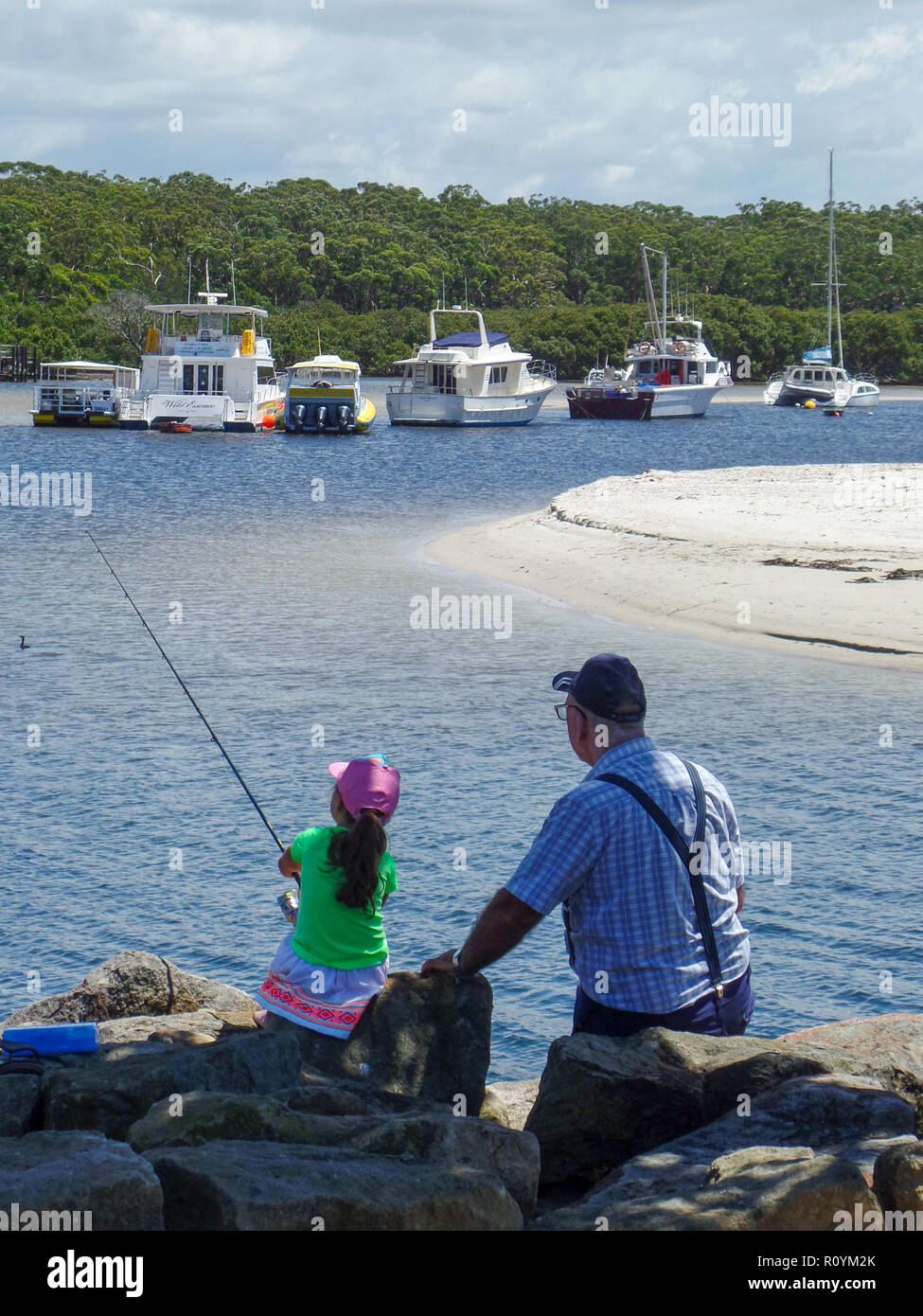 Grandfather bonds with granddaughter while fishing. Family fishing adventure. Stock Photo