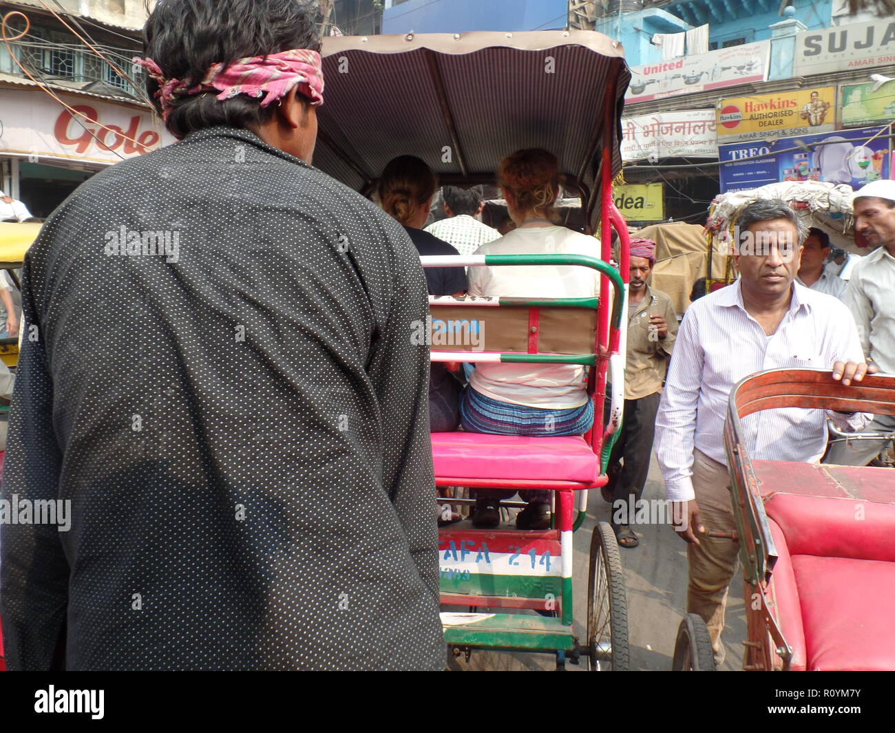 Tourist on rickshaws make way through the crowded market streets of Old Delhi, India. Stock Photo