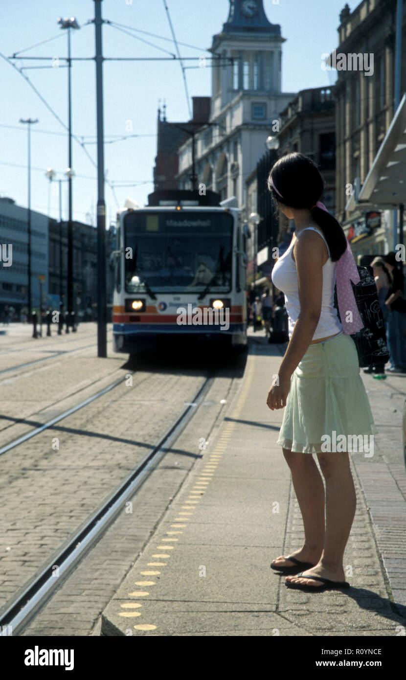 teenage girl university student waiting for oncoming tram, Sheffield, England Stock Photo