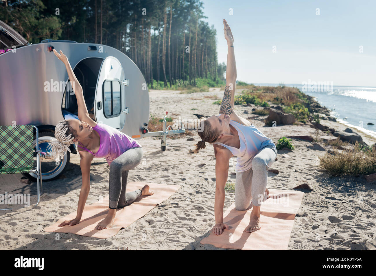 Modern healthy couple stretching their bodies after night in compact trailer Stock Photo