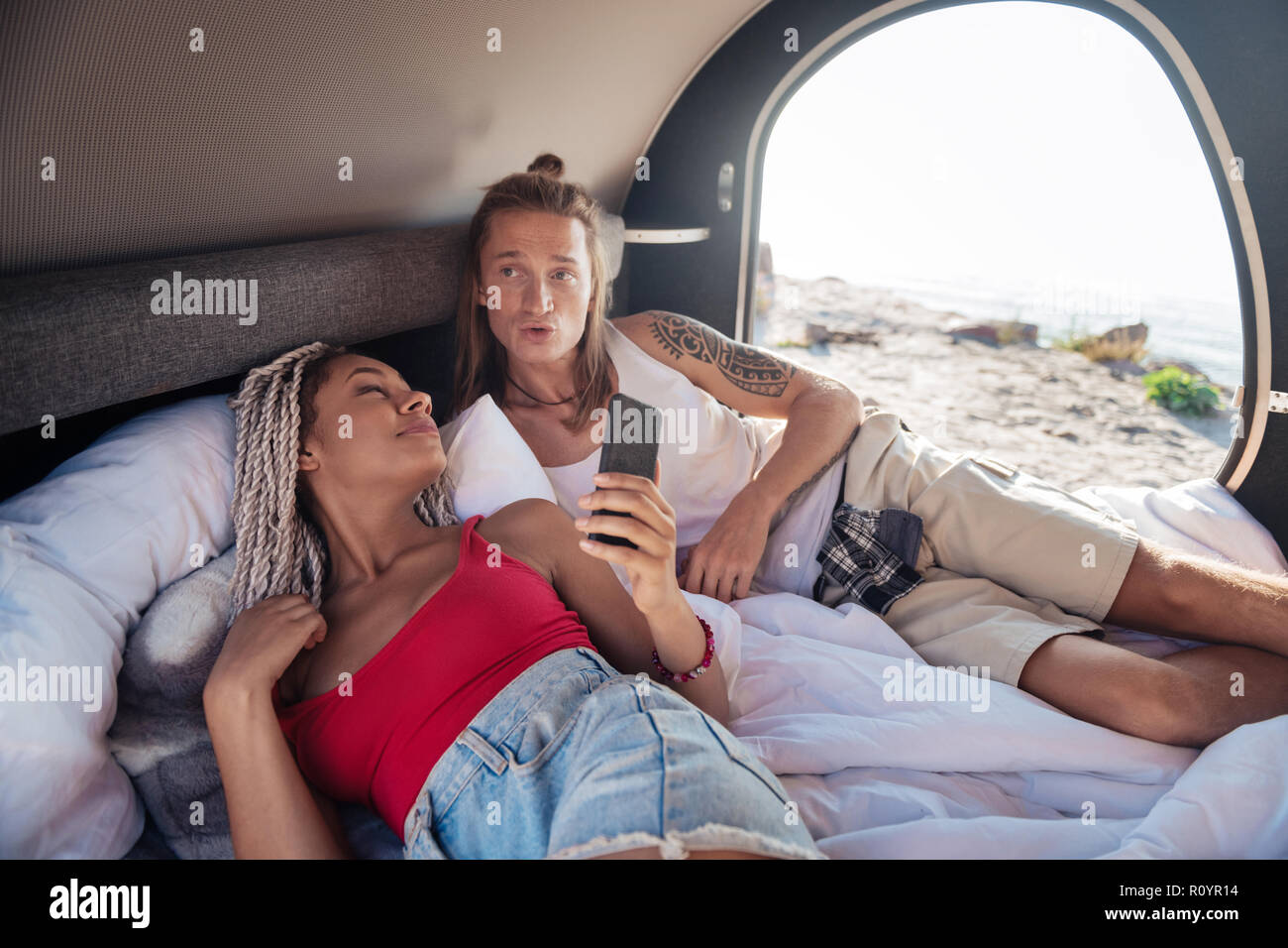Young couple of travelers waking up in compact trailer in the morning Stock Photo