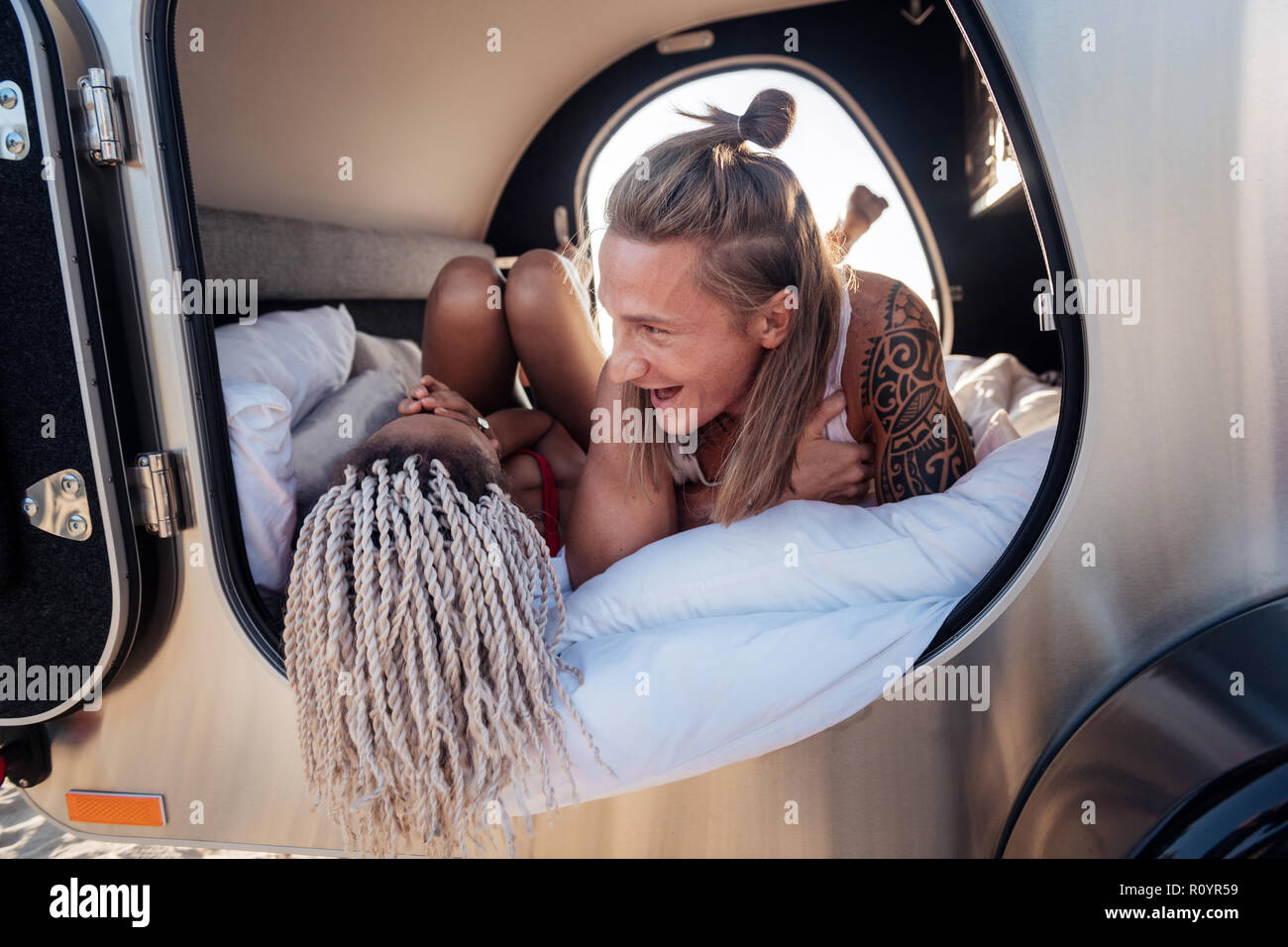 Handsome man with tattoo laughing while speaking with his funny girlfriend Stock Photo