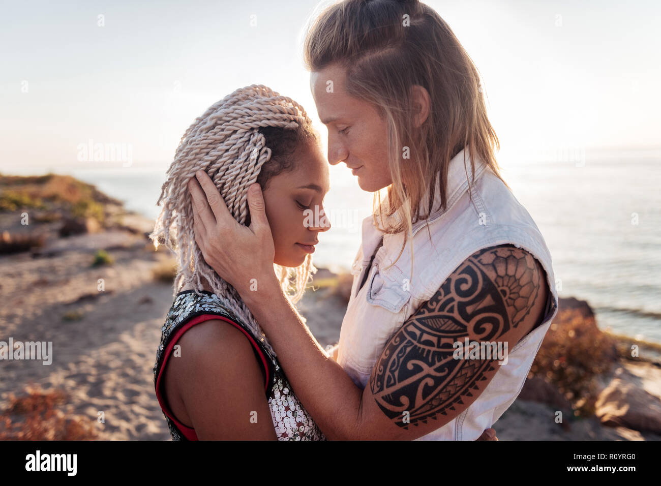 Blonde-haired man with tattoo on his hand hugging his cute girlfriend Stock  Photo - Alamy