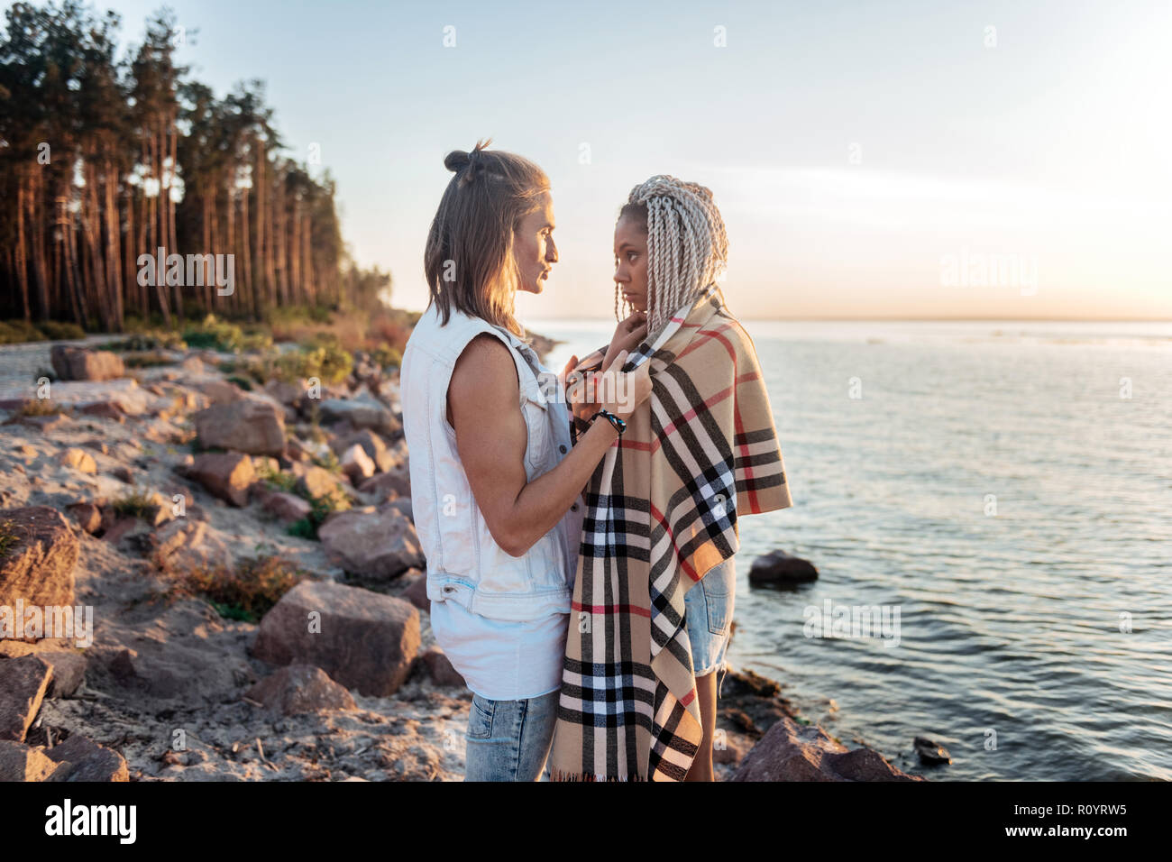 Caring loving man giving his girlfriend plaid on cold summer evening Stock Photo