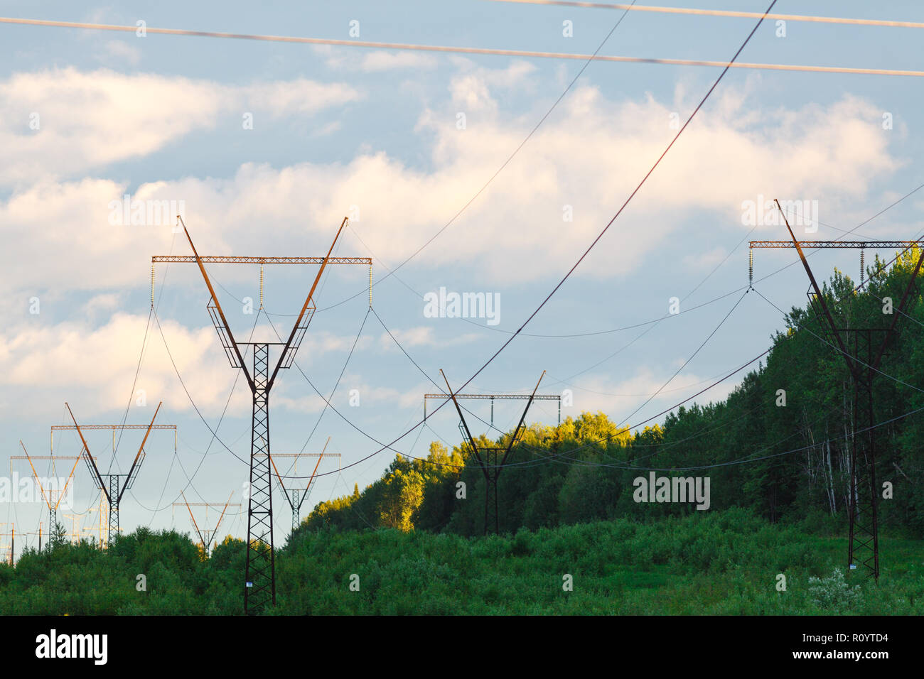 high voltage power pylons against blue sky and sun rays Stock Photo - Alamy