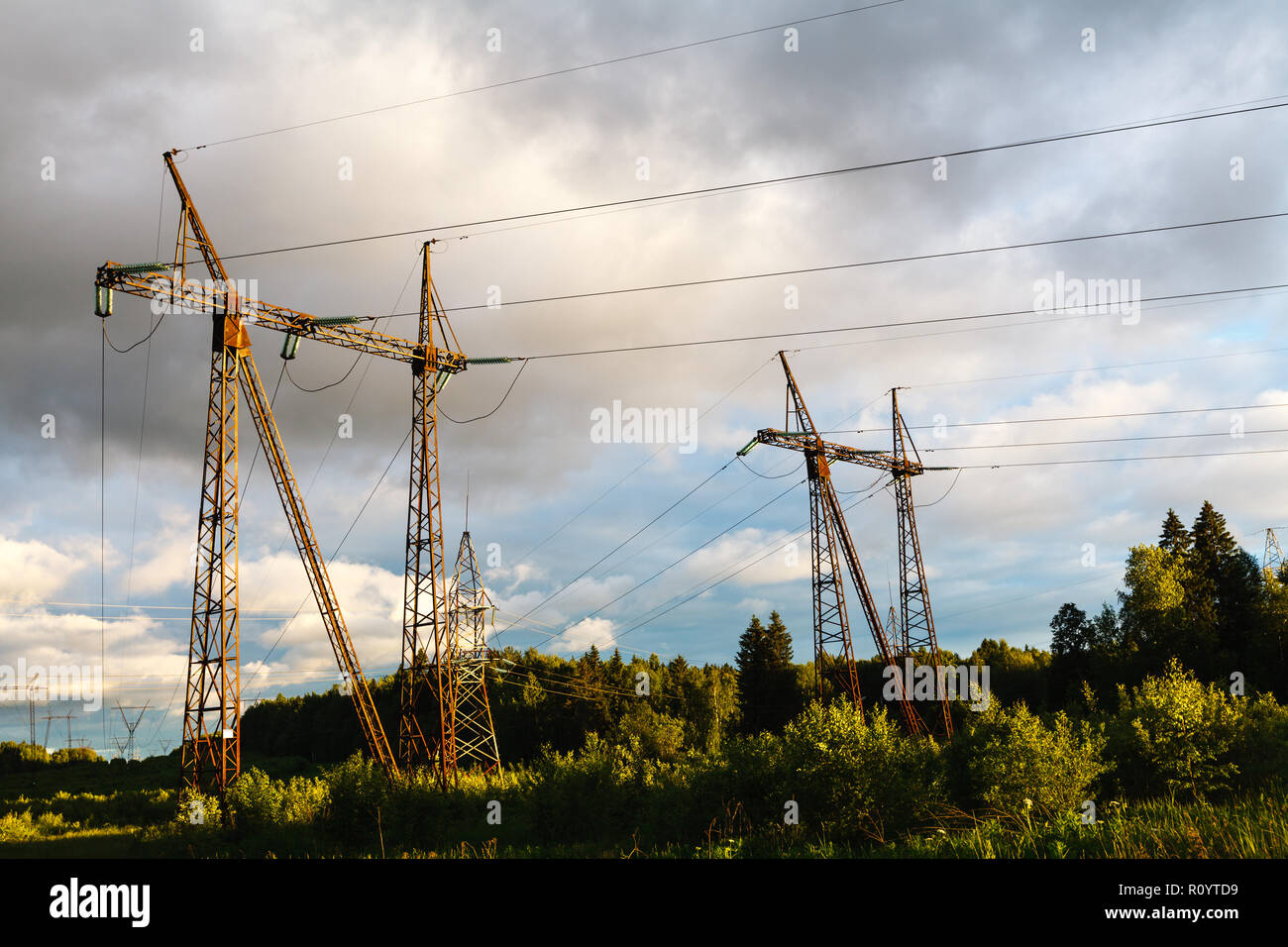 high voltage power pylons against blue sky and sun rays Stock Photo - Alamy