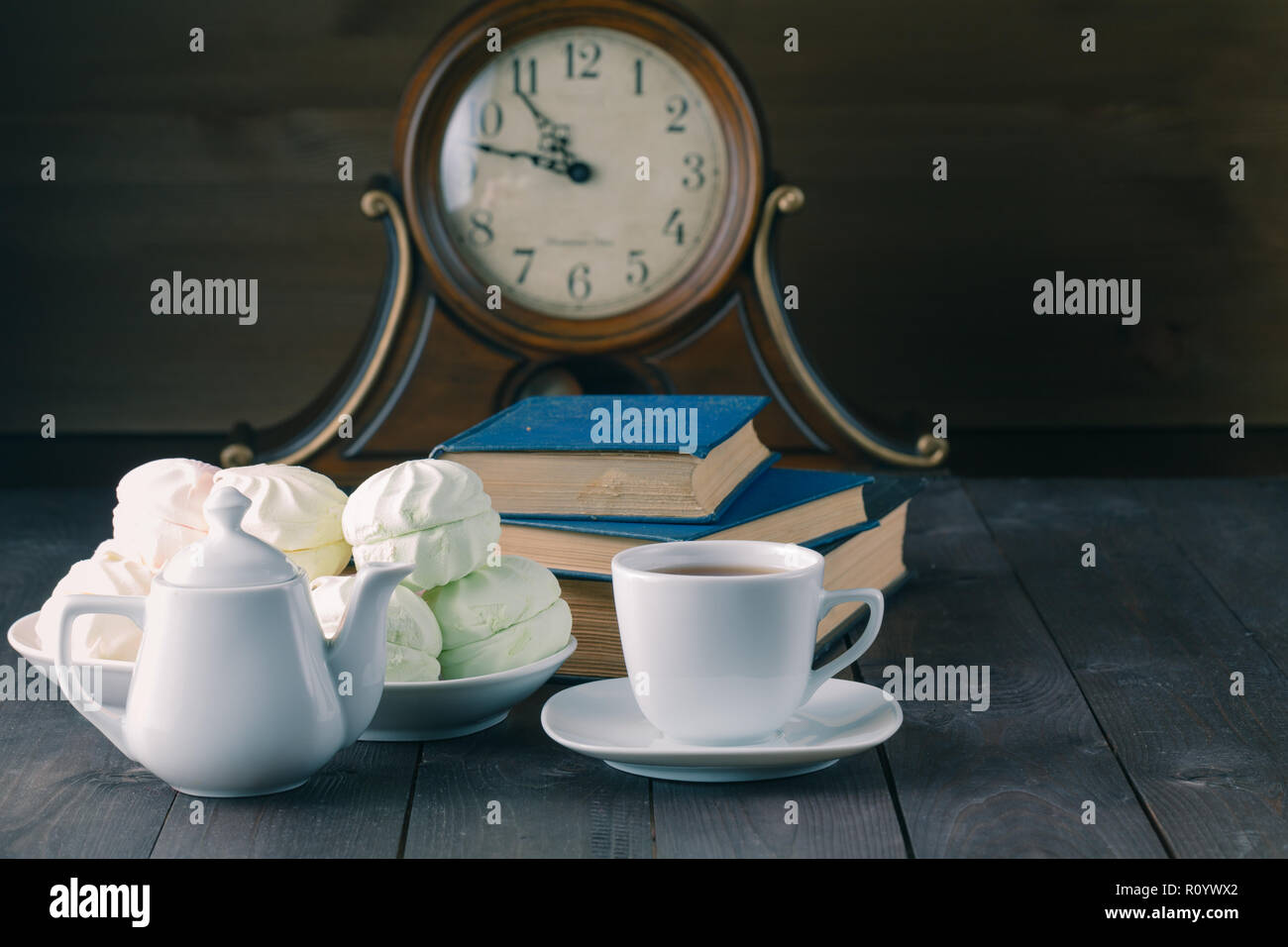 Evening with hot tea, sweets and books on wood table Stock Photo - Alamy