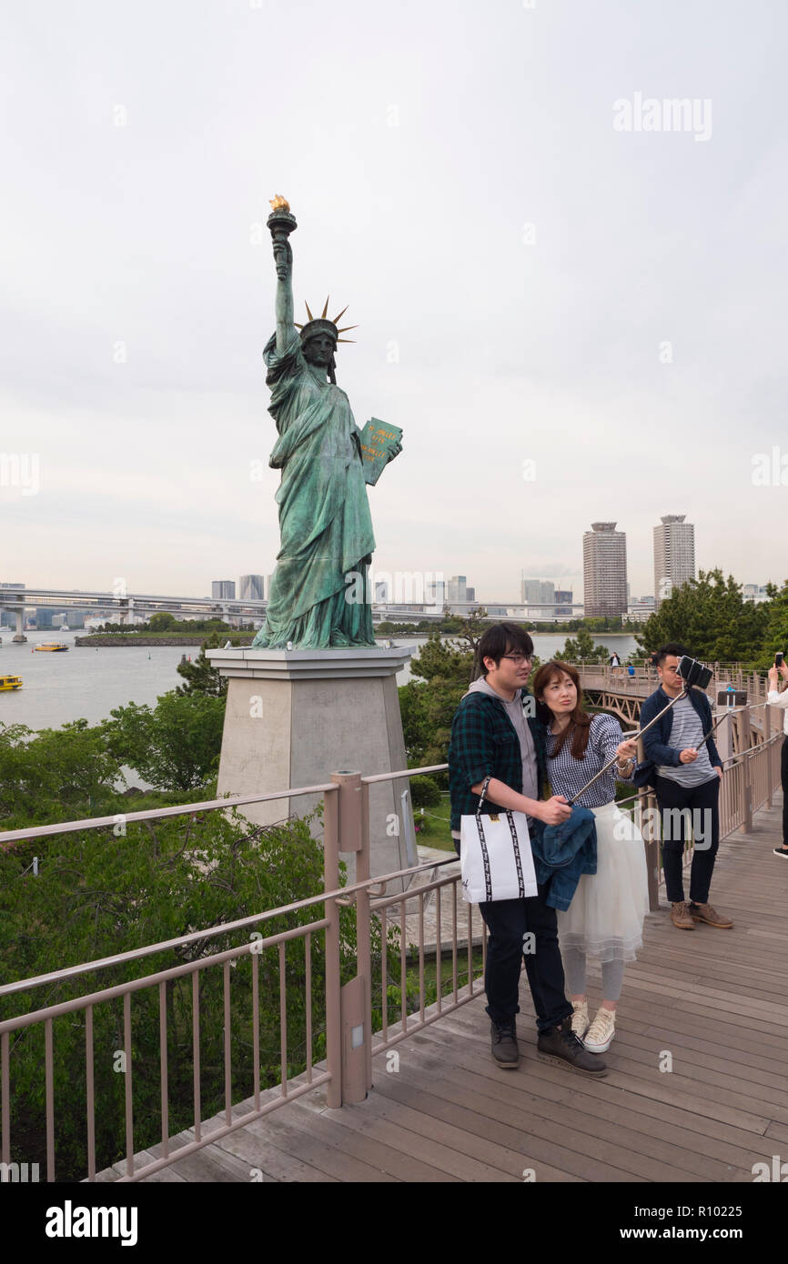People take photos near the Statue of Liberty in Odaiba Seaside park in