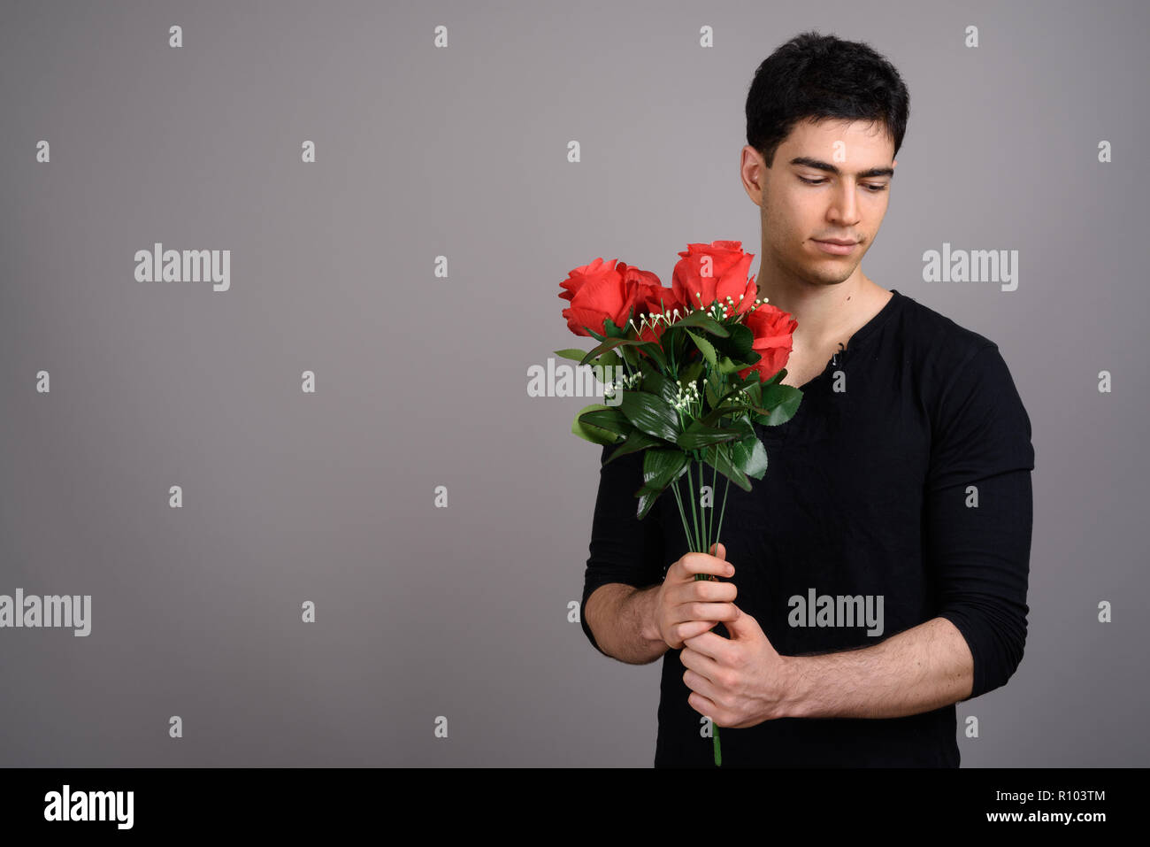 Portrait of young handsome man against gray background Stock Photo - Alamy