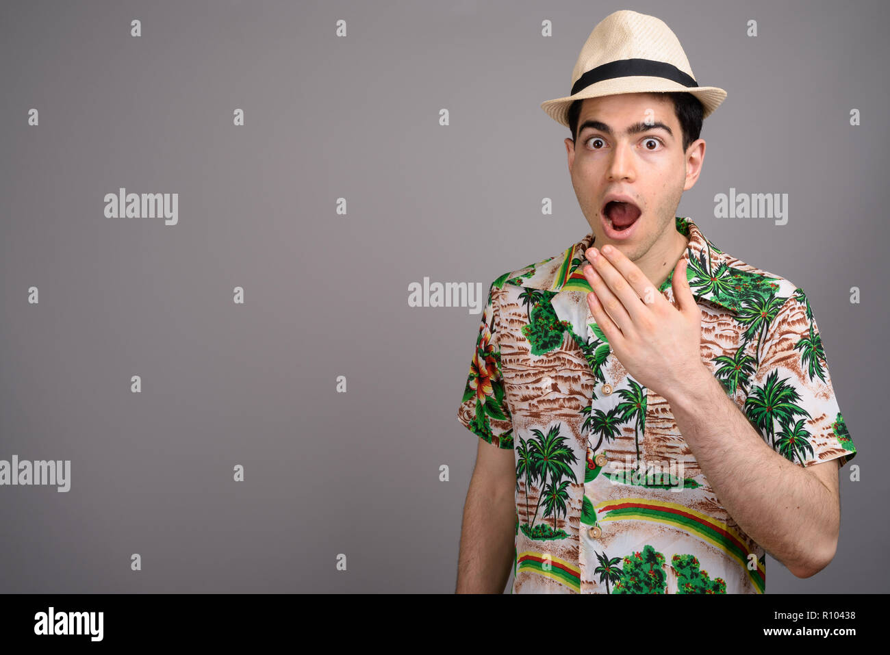 Young handsome tourist man ready for vacation against gray backg Stock Photo