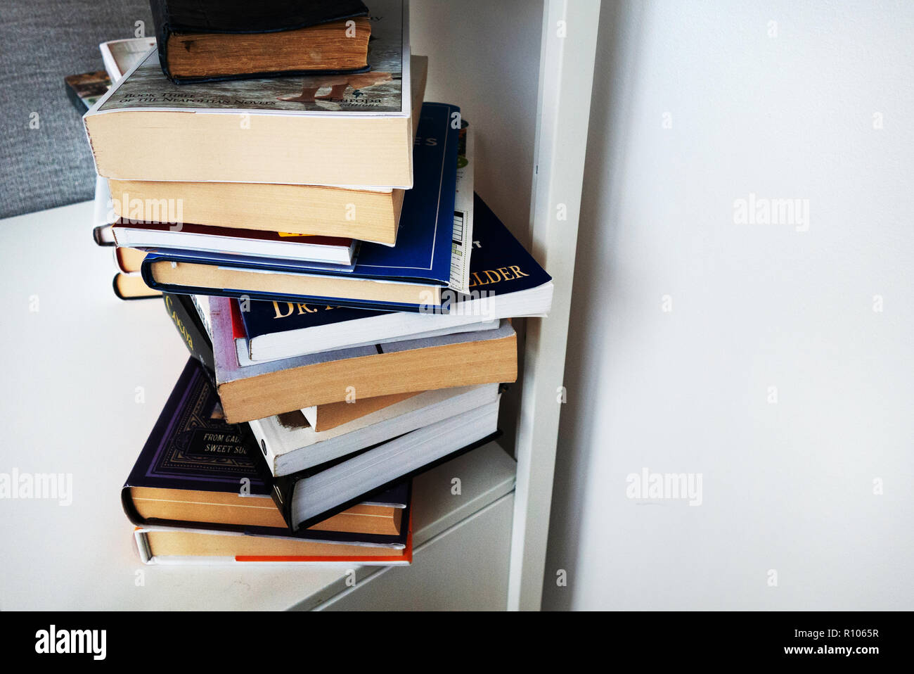 book shelf with a pile of hardbacked and paperback books on a white shelf, no copy Stock Photo