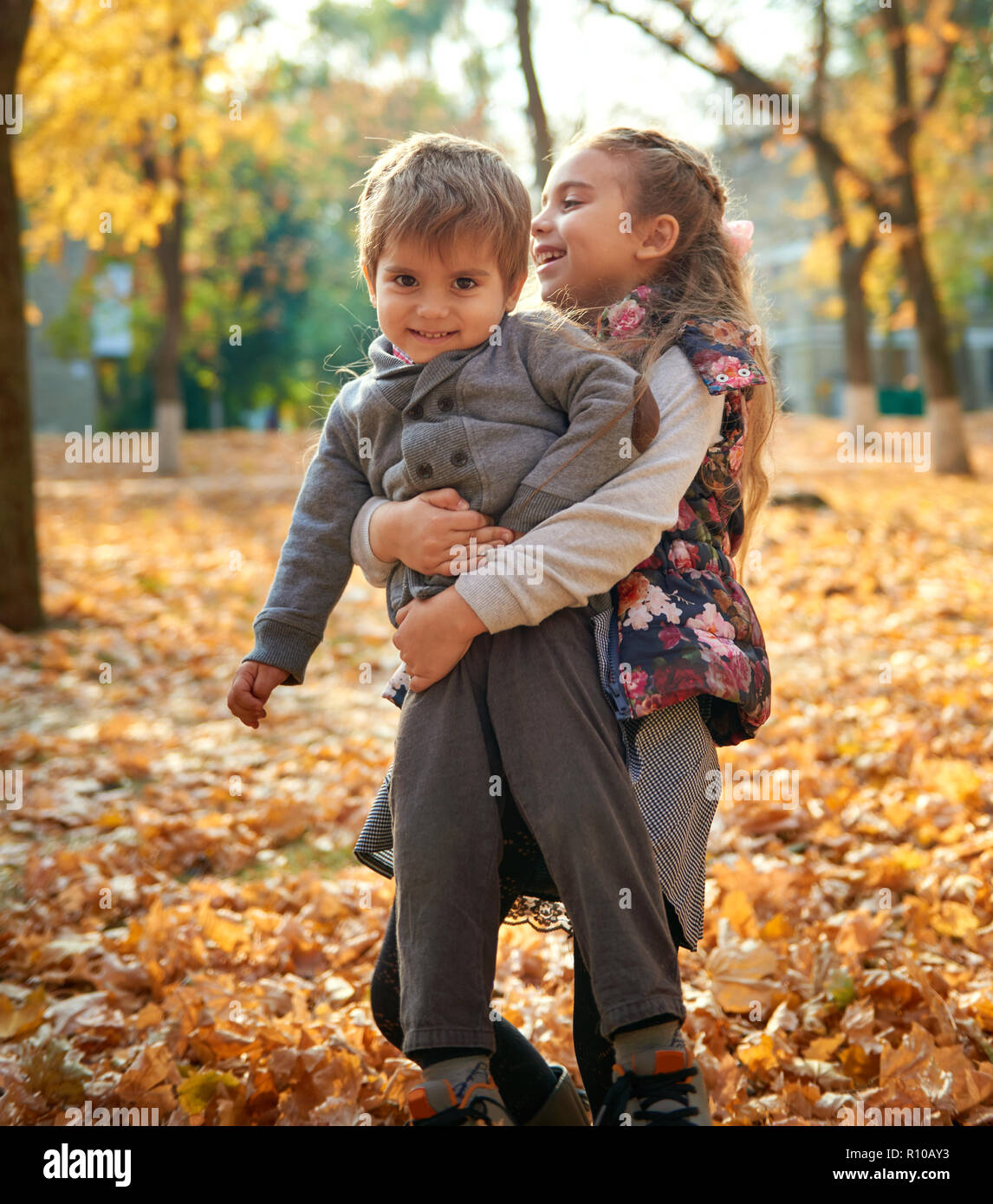 Children are playing on fallen leaves in autumn city park. Stock Photo