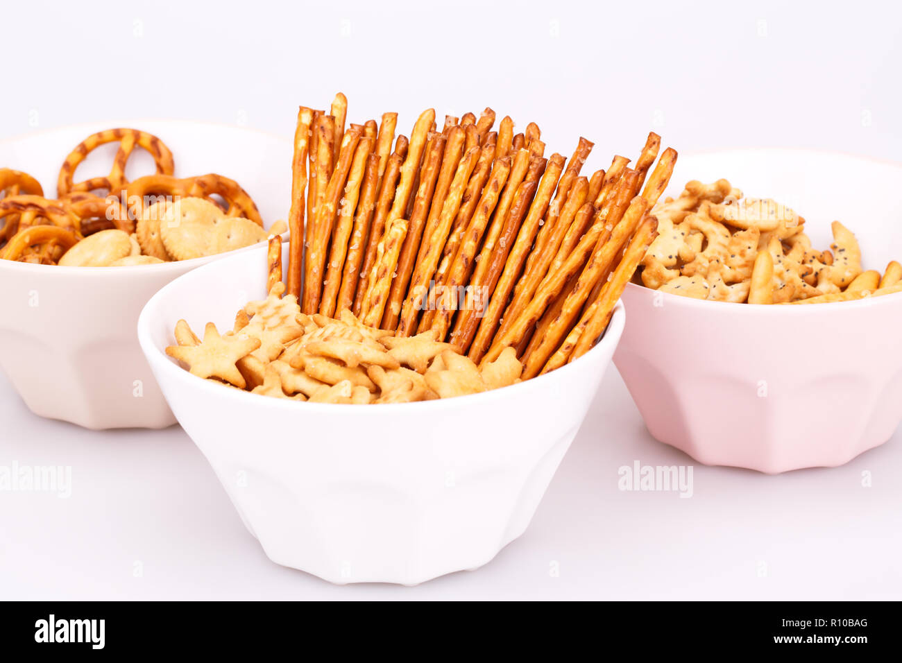 Different salted crackers in bowls on white background. Stock Photo