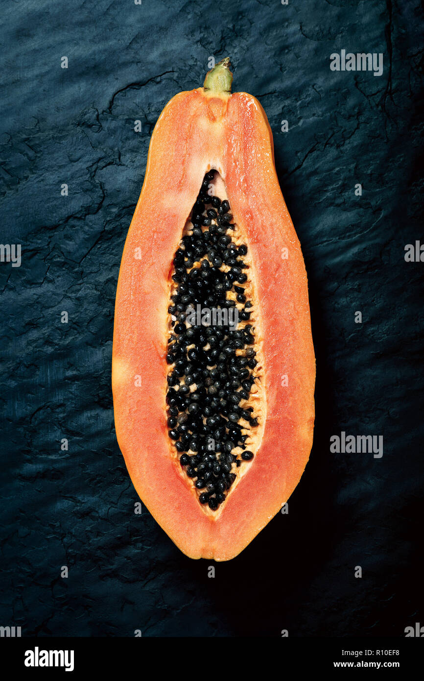 Papaya (Paw Paw) sliced in half and viewed from above on dark blue black slate rock Stock Photo
