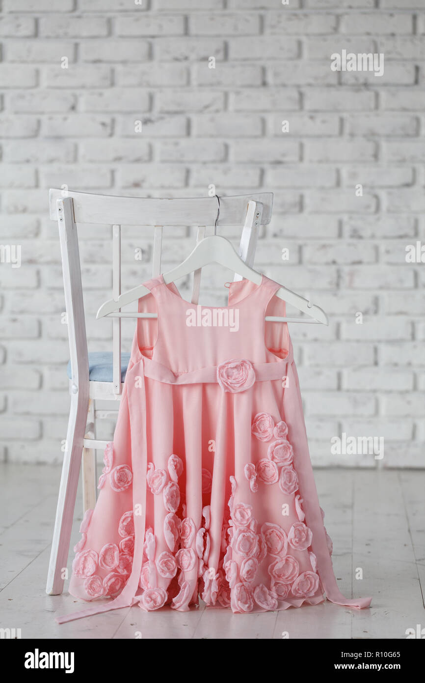 summer children's dresses hang on hangers on the back children's chair