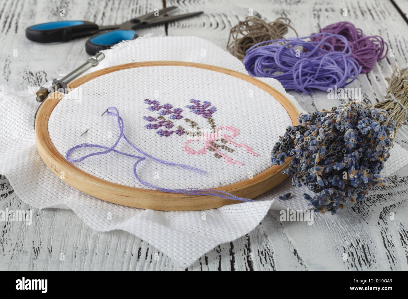 Embroidery hoop and multicolored accessories on white linen canvas with  spools of thread, needle and scissors Stock Photo - Alamy