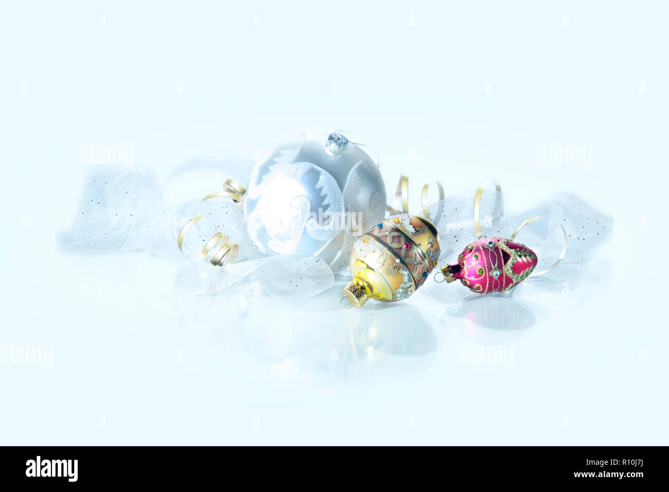 Ornate Christmas baubles and ribbon on white surface Stock Photo