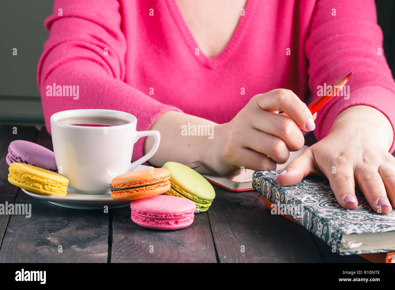 Female hands holding cup of hot beverage and drawing with pencil ...