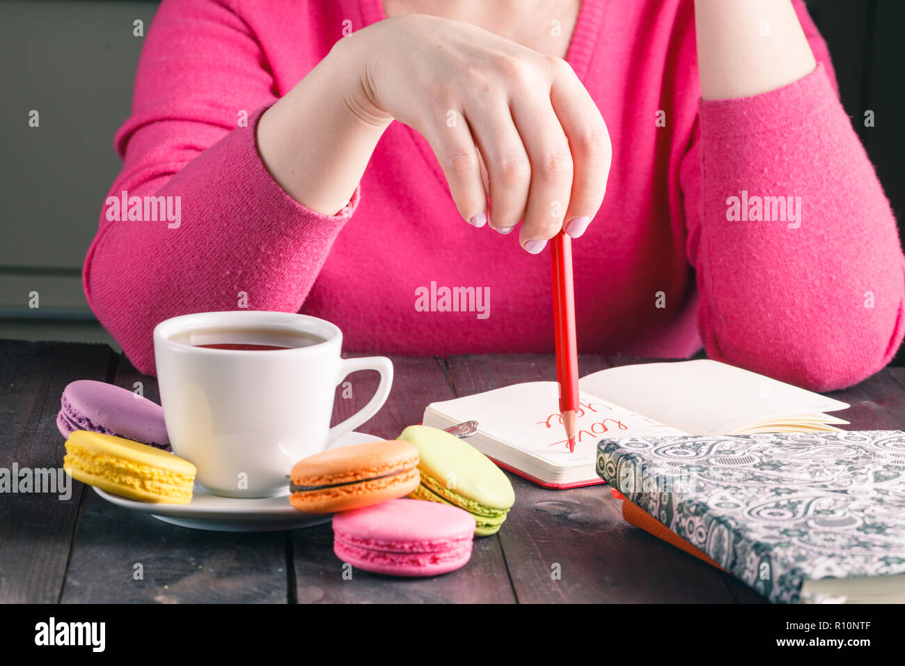 Female hands holding cup of hot beverage and drawing with pencil ...