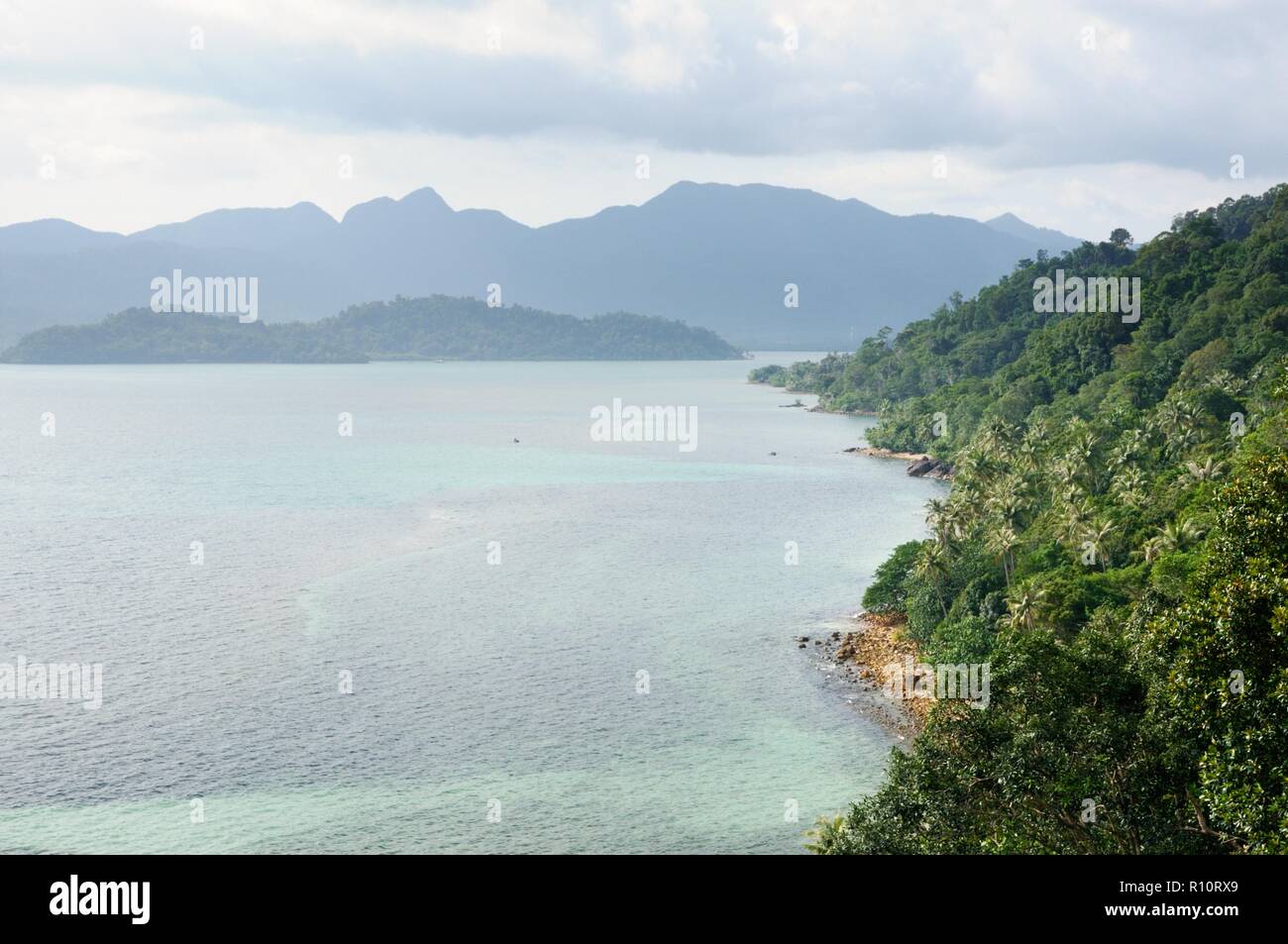 Bird eye view of tropical landscape with stone coastline, coconut palm trees, tropical sea and mountains on tropical Koh Chang island in Thailand Stock Photo