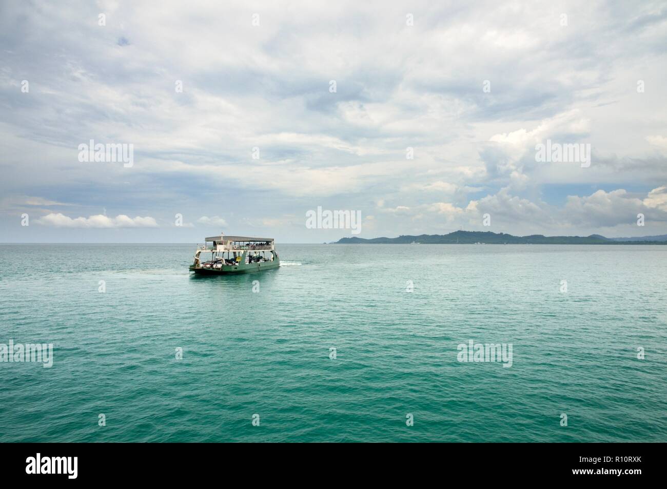 Landscape with turquoise tropical sea, cargo ferry, scenic clouds and tropical Koh Chang island on horizon in Thailand Stock Photo