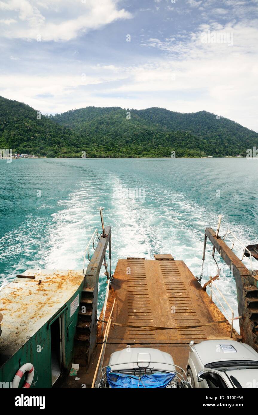 Ferry ramp and trace on the water of tropical sea behind ferry, with tropical Koh Chang island on horizon in Thailand Stock Photo