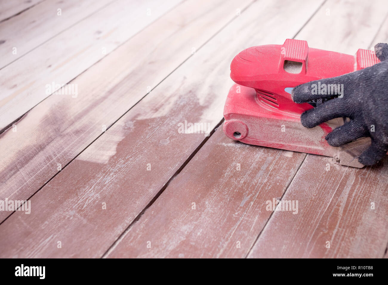Wood floor polishing maintenance work by grinding machine. Men's hands