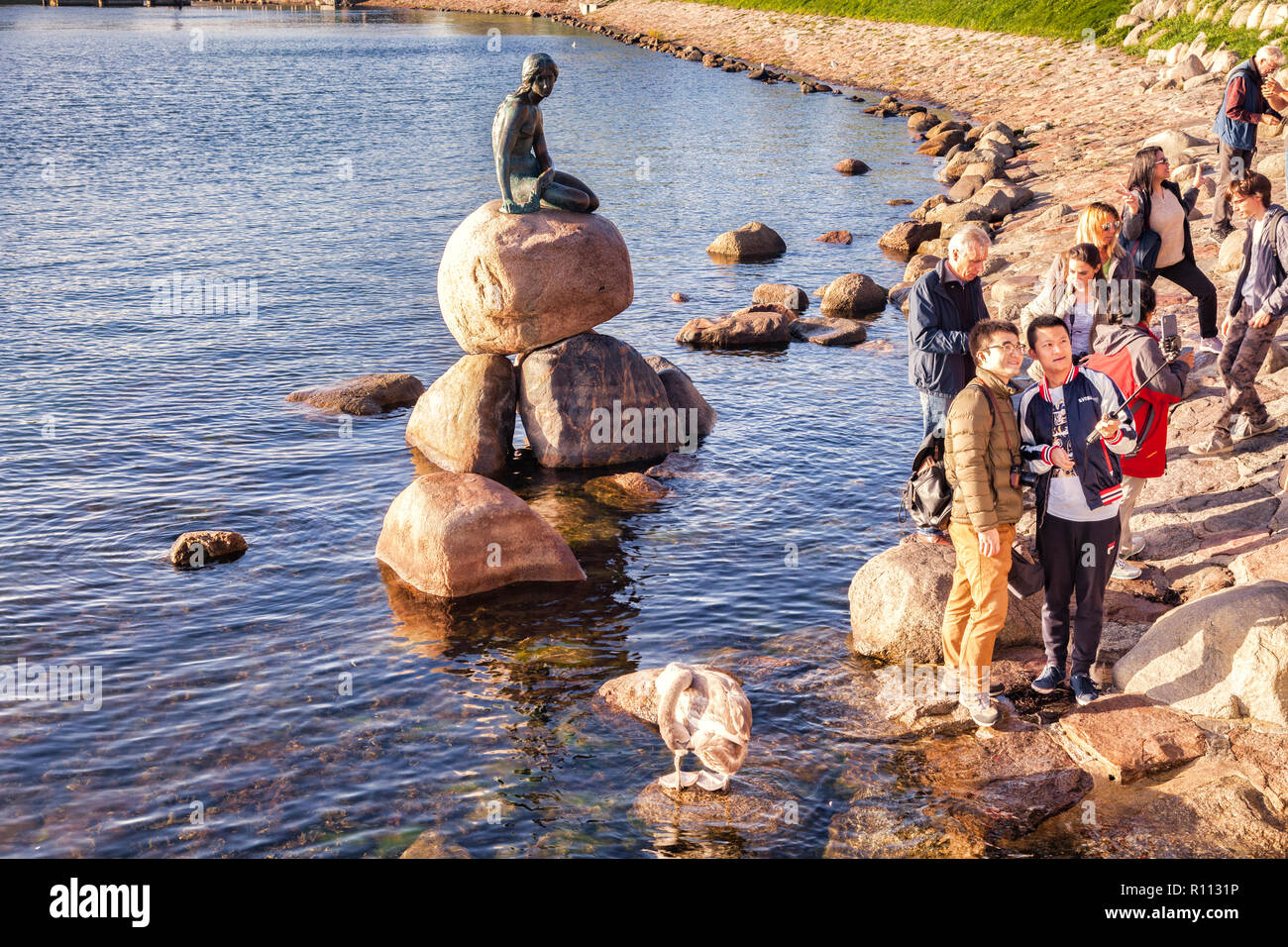 23 September 2018: Copenhagen, Denmark - Asian tourists taking selfies with a selfie stick at the  Little Mermaid, the famous bronze statue by... Stock Photo