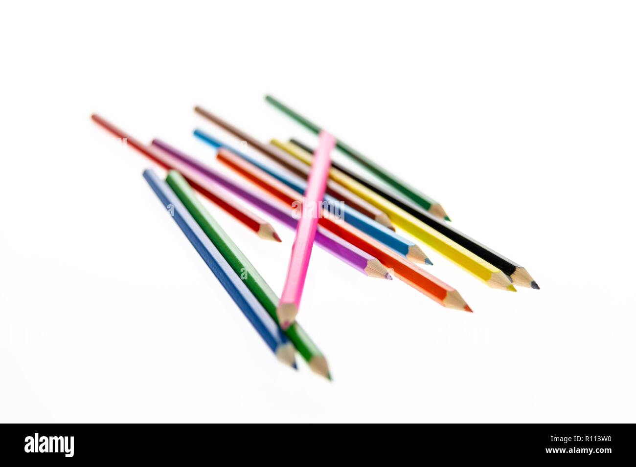 Coloured pencils randomly arranged on a white background. Colored pencil crayons.  Pencils are sharpened ready for drawing or sketching. Stock Photo