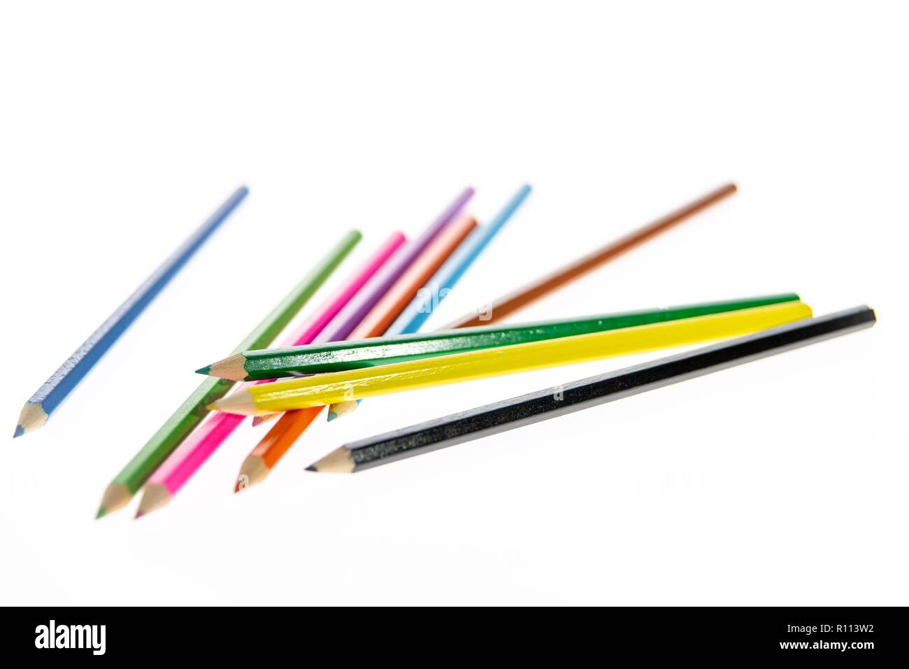 Coloured pencils randomly arranged on a white background. Colored pencil crayons.  Pencils are sharpened ready for drawing or sketching. Stock Photo