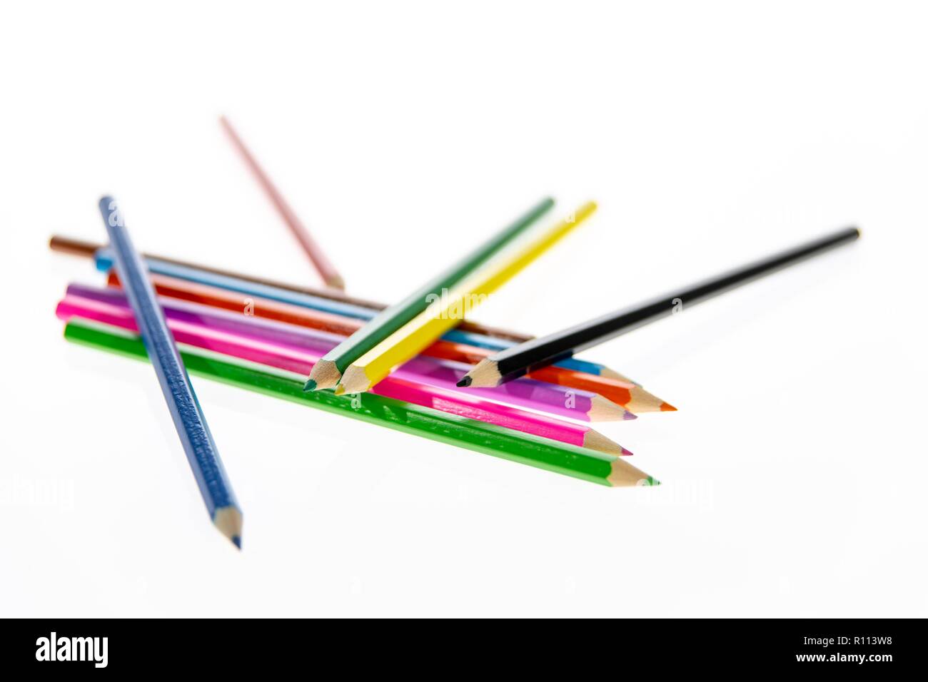 Coloured pencils randomly arranged on a white background. Colored pencil crayons.  Pencils are sharpened ready for drawing or sketching. Stock Photo