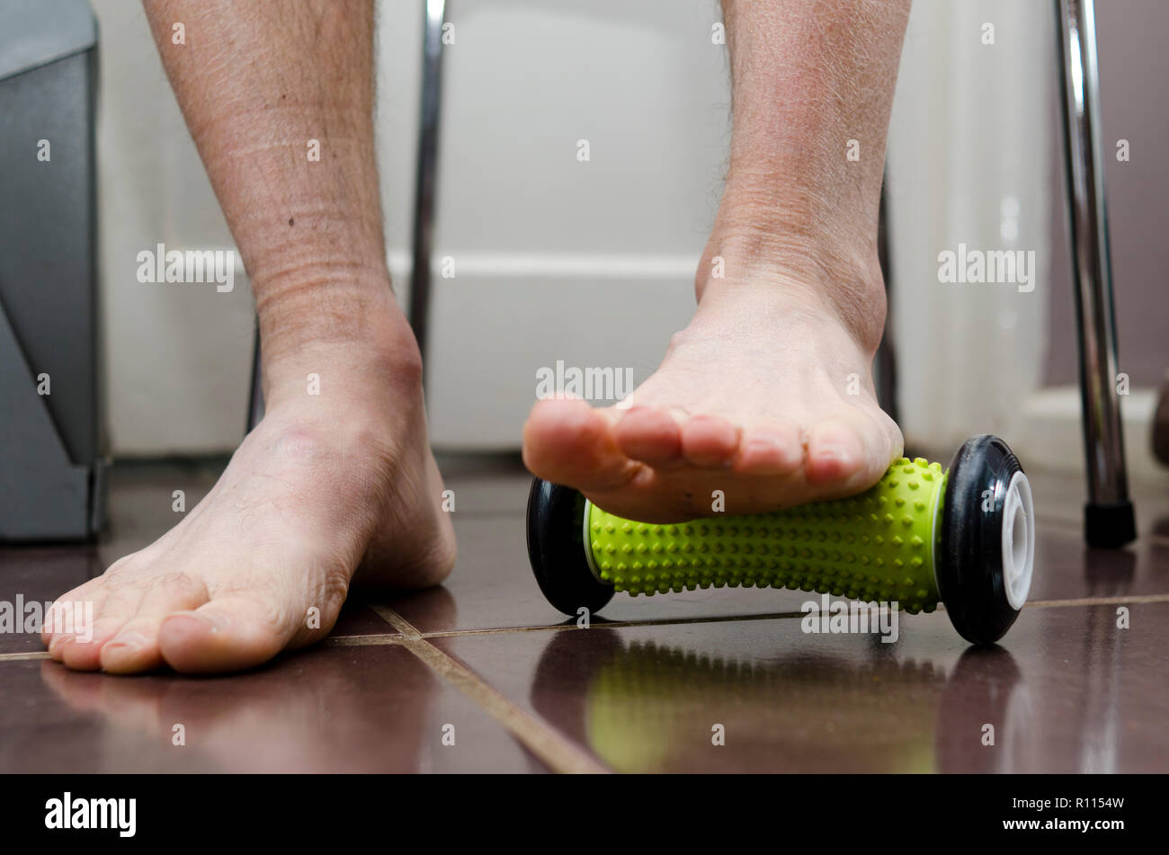 Plantar Fasciitis. Sufferer using a foot roller at home for treatment. Stock Photo