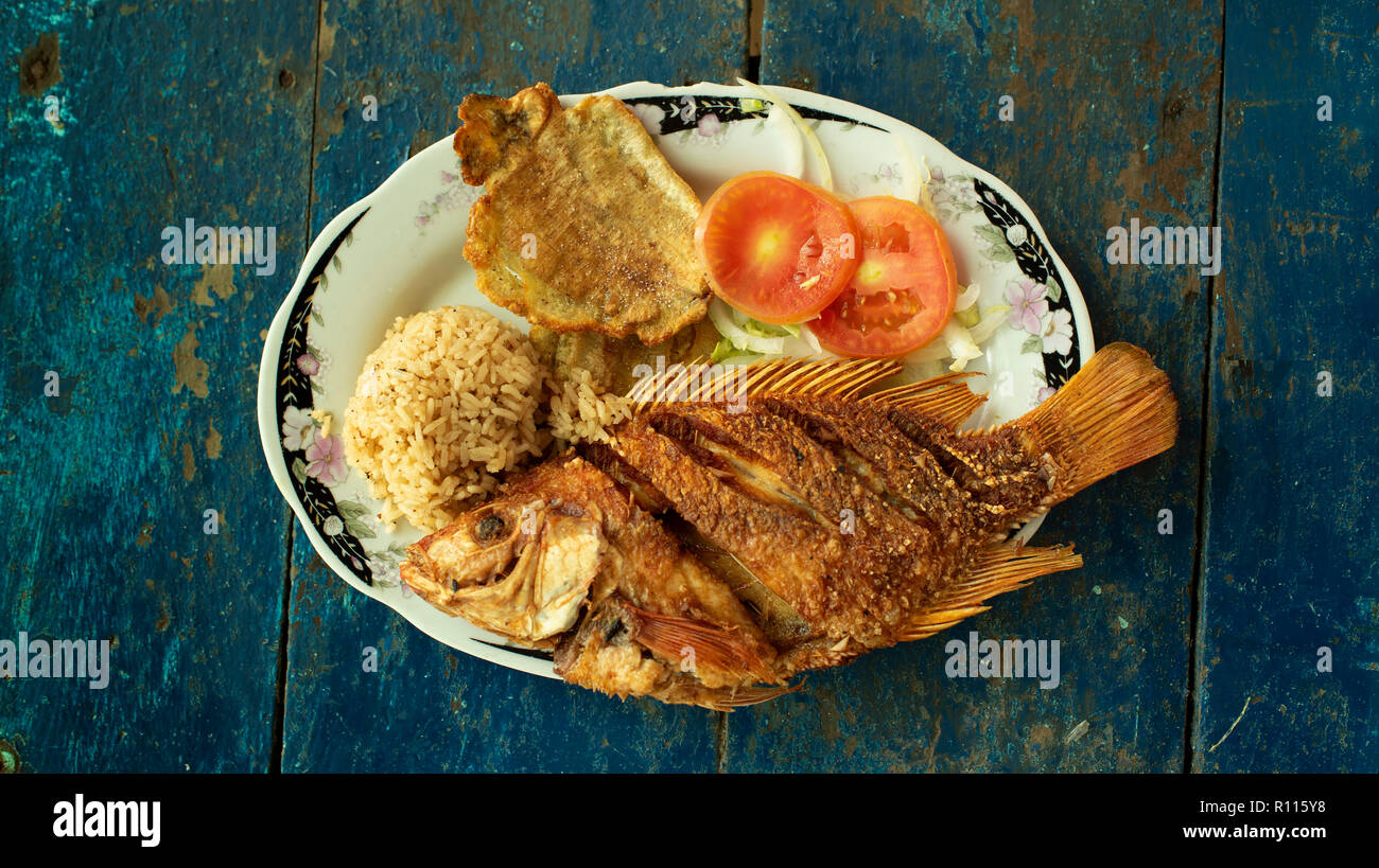 A typical Caribbean meal with fried fish, coconut rice and patacones (twice-fried plantain slices). Playa Cristal, Tayrona Park, Colombia. Sep 2018 Stock Photo