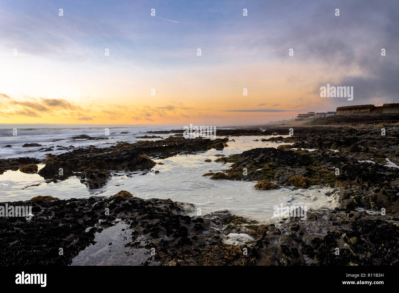 Seascape at sunset. Beacon, rocks, waves. Warm light. Wide-Angle. Stock Photo