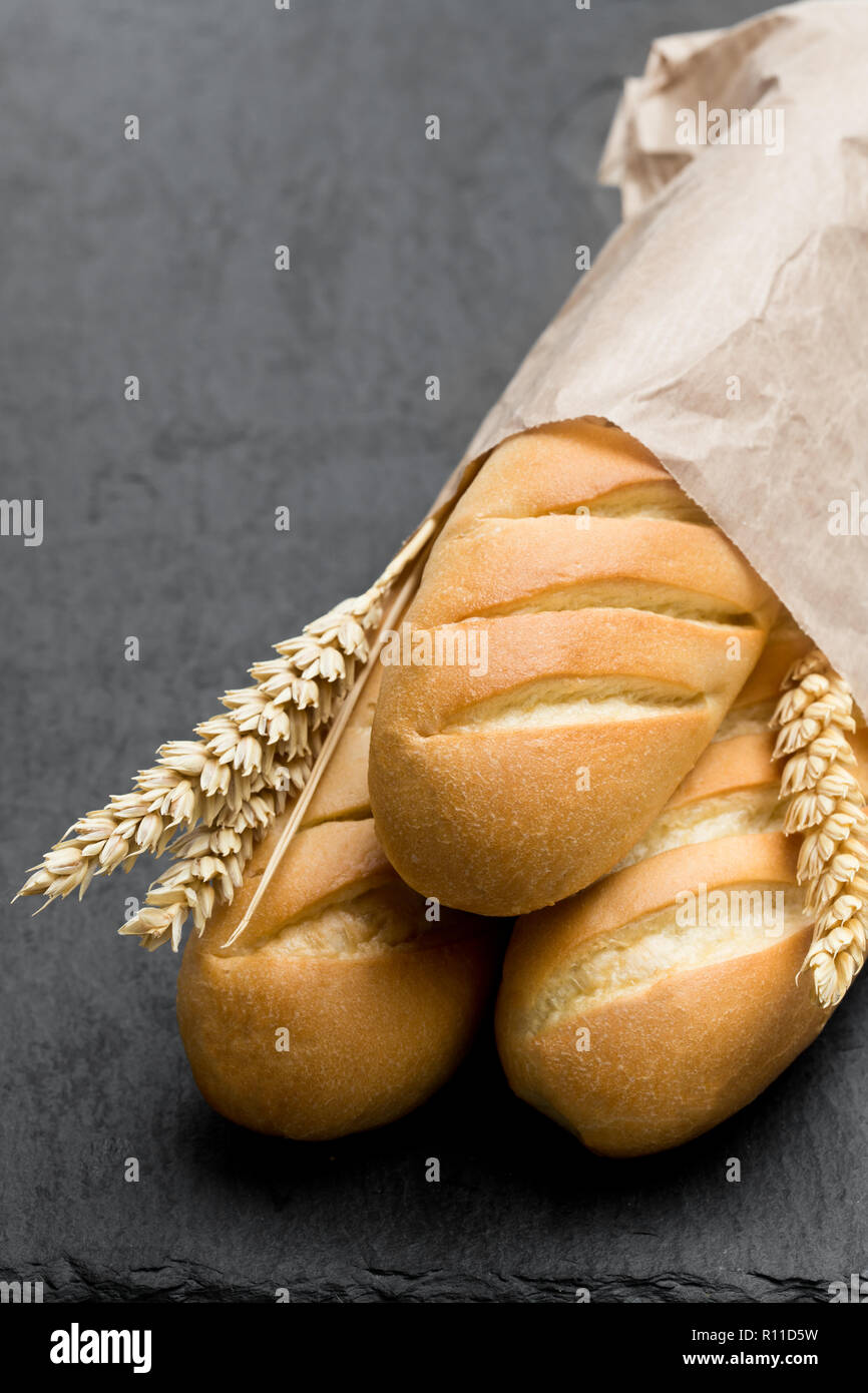 Delicious baguettes in paper bag on black stone background Stock Photo ...