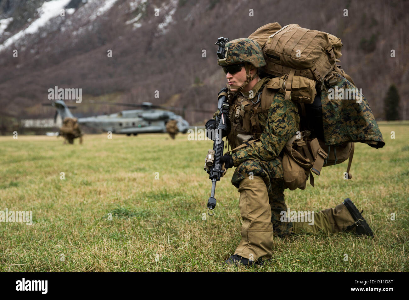 A U.S. Marine Corps holds a position after disembarking a CH-53E Super Stallion helicopter during Exercise Trident Juncture 18 October 31, 2018 in Gjora, Norway. The multi-national exercise is the largest NATO exercise since 2015, and includes more than 50,000 military members from 31 countries. Stock Photo
