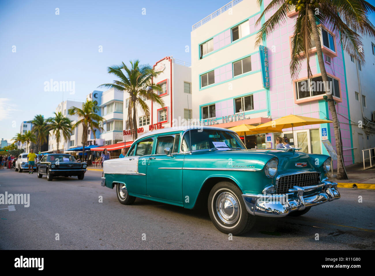 MIAMI - CIRCA JANUARY, 2018: A line of classic cars stand parked on front of iconic colorful Art Deco architecture on Ocean Drive. Stock Photo
