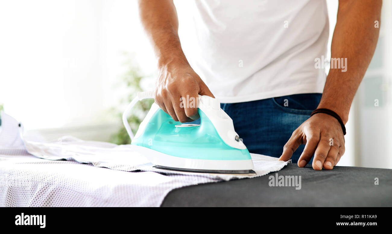Young Happy Man Ironing Clothes at home Stock Photo