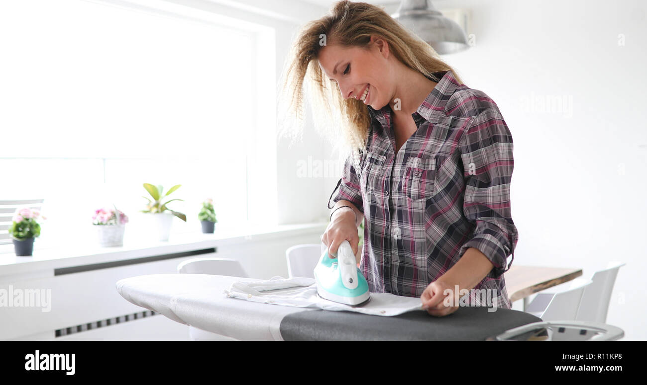 Young beautiful woman ironing clothes at home Stock Photo