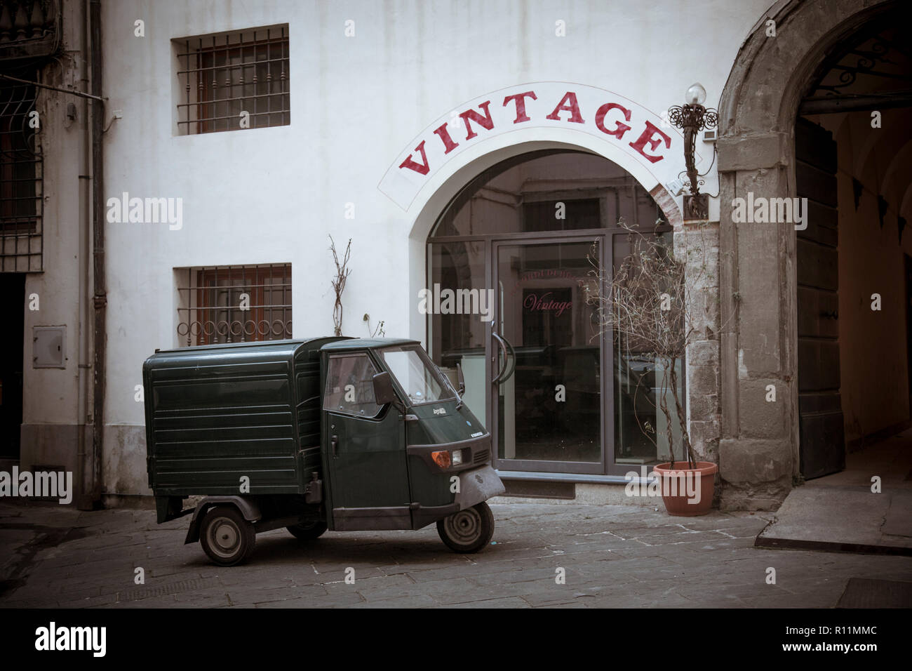 A miniscule Piaggio Ape 50 delivery truck packed in the back streets of Lucca, Italy. Stock Photo