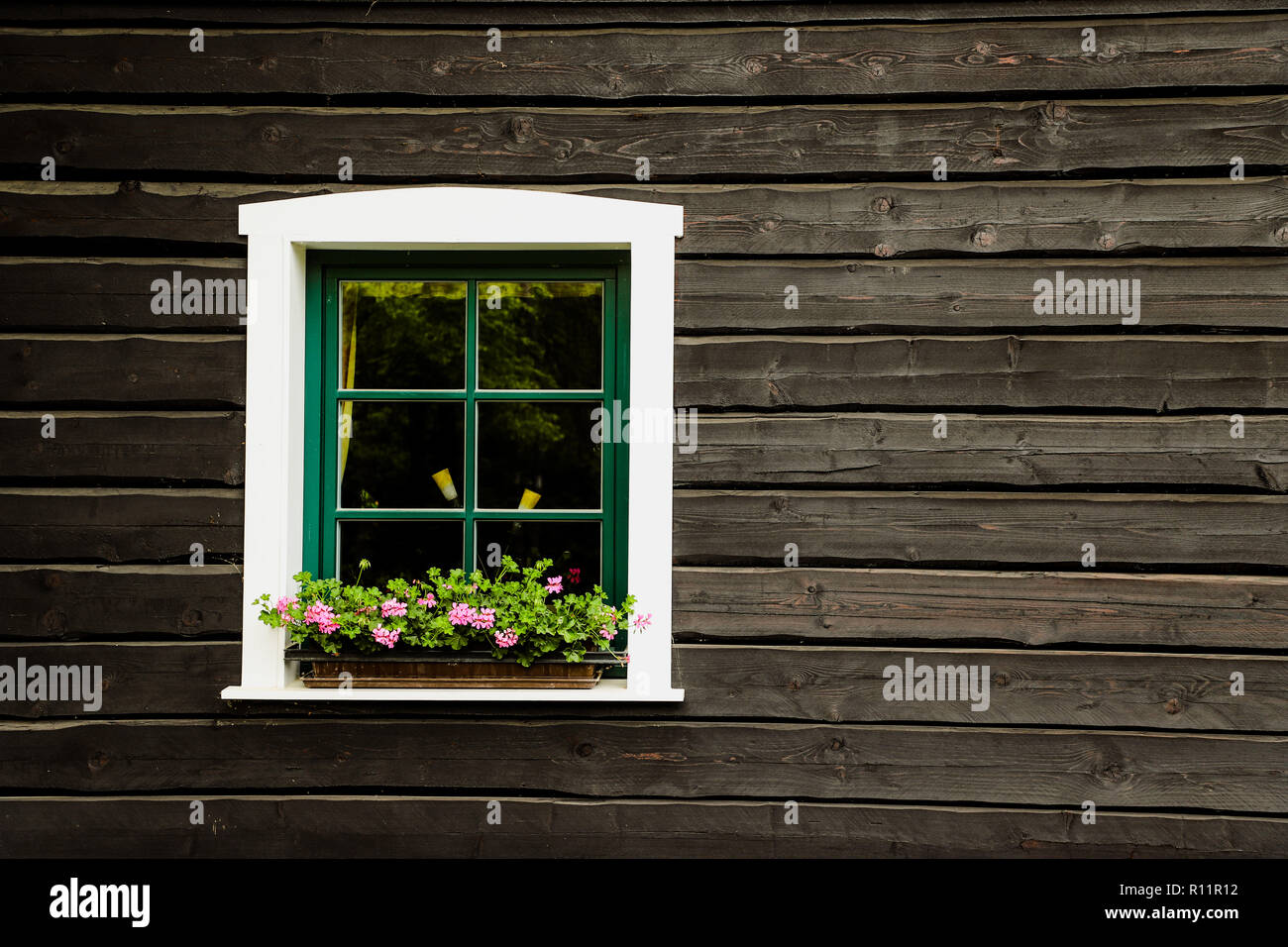White window with flowers and green frame on a countryside house or ...