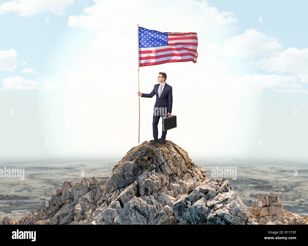 Successful businessman on the top of a mountain holding victory flag ...