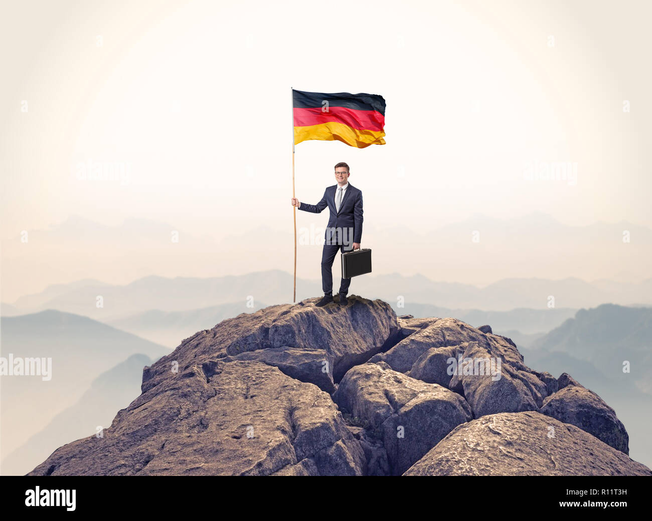 Successful businessman on the top of a mountain holding victory flag ...