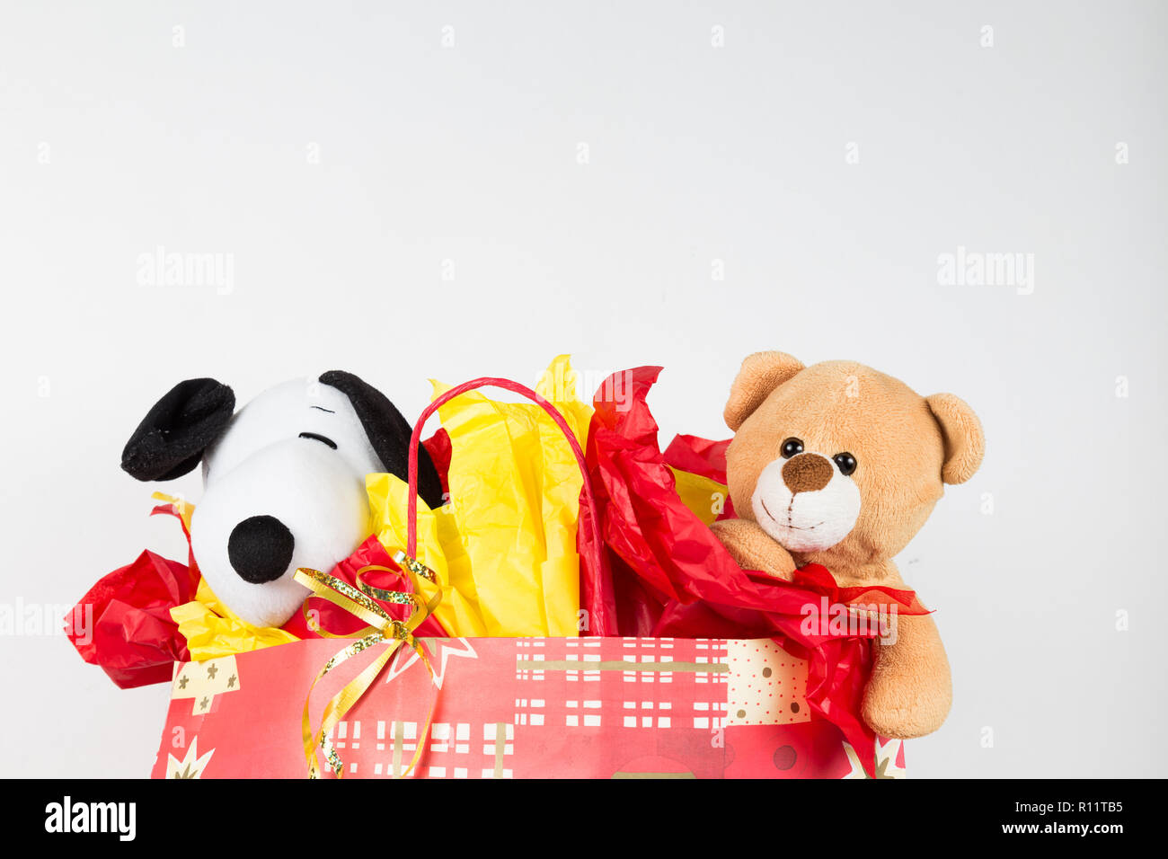 Stuffed toys wrapped with paper and popping out from a gift bag Stock