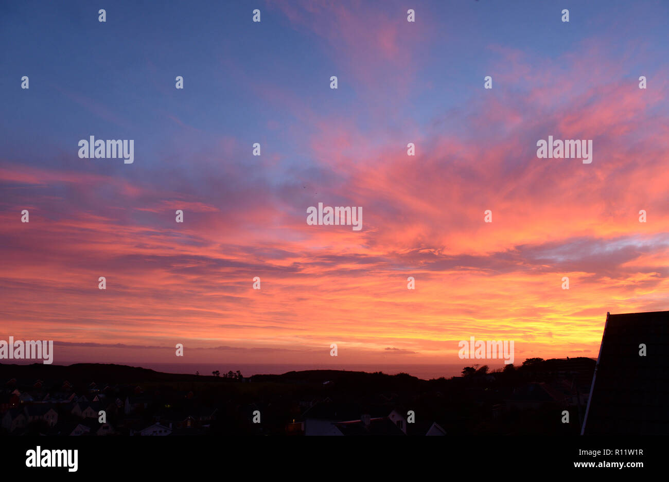 Sunset at Mumbles. A Setting Sun disappears below the horizon causing atmospheric refraction creating the beautiful spectrum of colours in the sky. Stock Photo