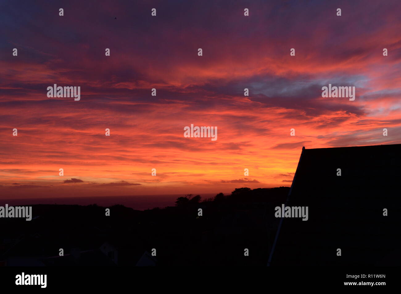 Sunset at Mumbles. A Setting Sun disappears below the horizon causing atmospheric refraction creating the beautiful spectrum of colours in the sky. Stock Photo